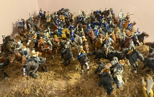A large collection of toy soldiers on horseback, arranged in a chaotic scene with detailed figures and terrain.