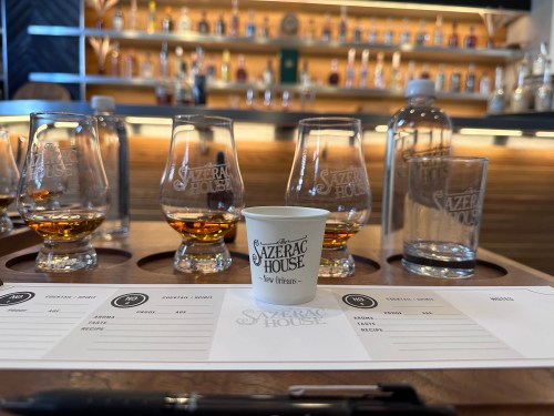 A tasting setup at Sazerac House featuring whiskey glasses, a small cup, a water bottle, and a tasting sheet.