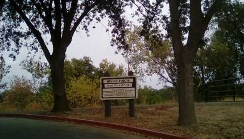 Sign for Irvine Finch Wildlife Access Site, surrounded by trees and autumn foliage.