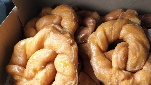 A box filled with golden, spiral-shaped sweet pastries, glistening with a sugary glaze.