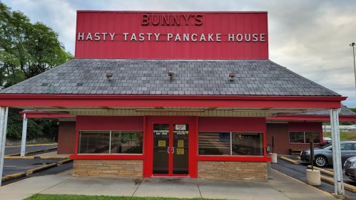 Exterior of Bunny's Hasty Tasty Pancake House, featuring a red roof and signage, with parking in front.