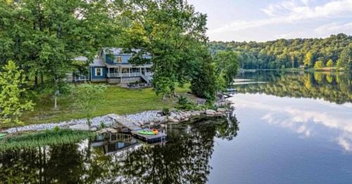 A blue vacation rental sits on a grassy yard overlooking a small lake in Kentucky.