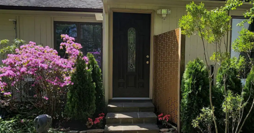 A welcoming front entrance with a dark door, surrounded by vibrant flowers and neatly trimmed shrubs.