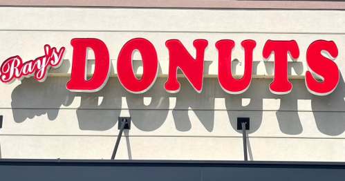 Sign for "Ray's Donuts" in bold red letters against a light-colored background.