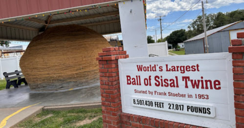 Sign for the world's largest ball of sisal twine, started by Frank Stoeber in 1953, with the twine ball displayed nearby.