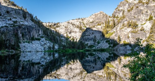 Rugged mountains and towering pine trees surround the shore and are reflected in the water at Northern California's Eagle Lake.