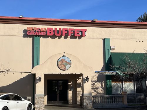 Exterior of Merced Grand Buffet with a clear blue sky and a white car parked in front.