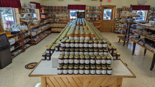 A store interior featuring rows of jars and bottles on tables, showcasing various preserves and products.