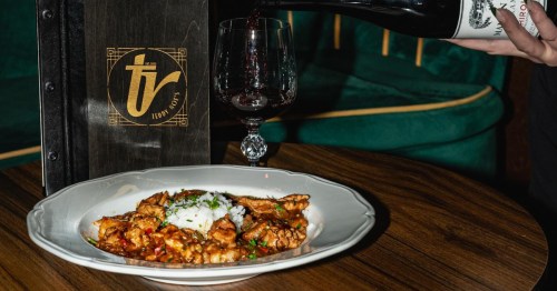 Red wine being poured next to a savory chicken and rice dish at Teddy Roe's in Albuquerque, New Mexico.