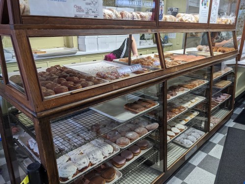 A display case filled with various donuts and pastries, showcasing colorful toppings and different flavors.