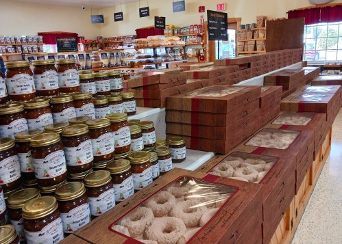 A store display featuring jars of honey and neatly arranged boxes of donuts on wooden shelves.