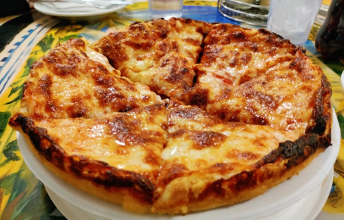 A freshly baked pizza with a golden crust, melted cheese, and a few toppings, sliced into eight pieces.