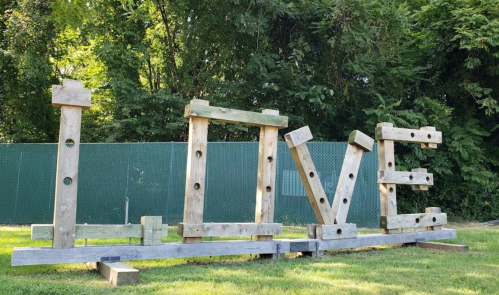 Wooden letters spelling "LOVE" in a grassy area, surrounded by trees and a fence in the background.