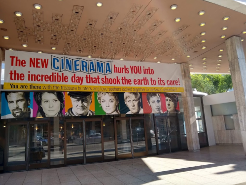 Banner for "The New Cinerama" featuring colorful portraits of characters, promoting an exciting cinematic experience.