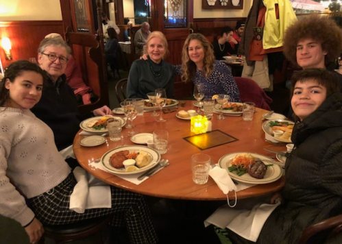 A group of six people enjoying a meal together at a round table in a cozy restaurant setting.