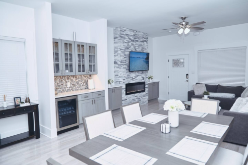 Modern open-concept living space featuring a dining table, kitchen with stone backsplash, and cozy seating area.
