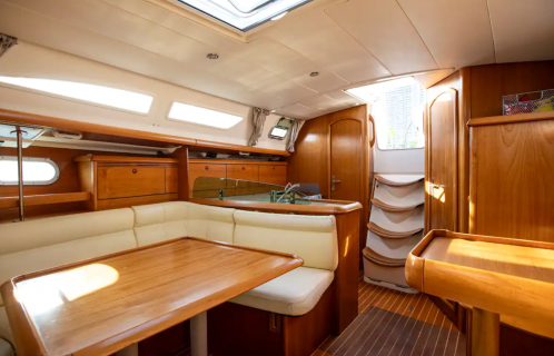 Interior of a sailboat featuring wooden cabinetry, a dining area, and natural light from windows.