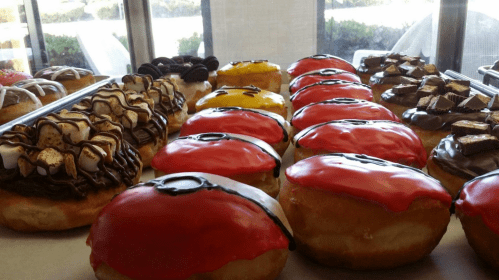 A variety of colorful donuts decorated like Poké Balls, with chocolate and other toppings on display.