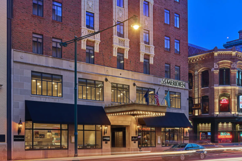 Exterior of a hotel building at dusk, featuring brick architecture and marquee lights, with streetlights illuminating the scene.