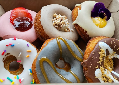 A box of six assorted donuts with various toppings, including fruit, glaze, and sprinkles.