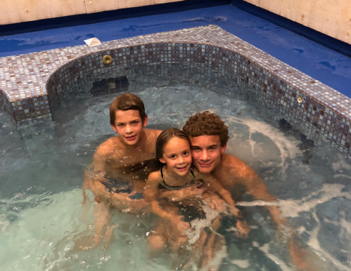 Three children play together in a hot tub, smiling and enjoying their time in the water.