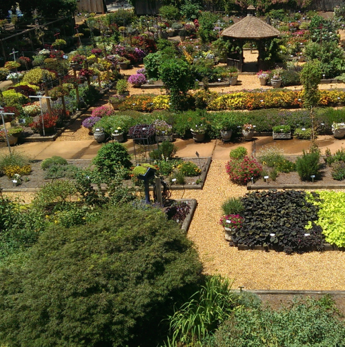 A vibrant garden filled with colorful flowers, neatly arranged paths, and a gazebo in the center.