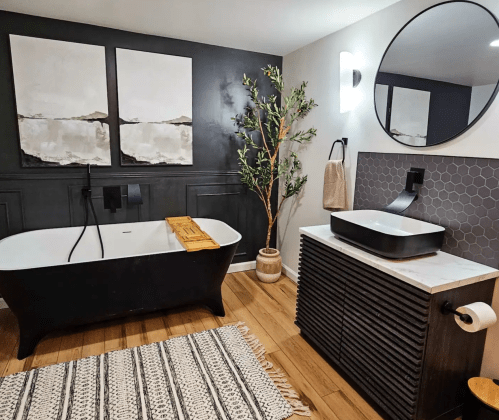 Modern bathroom featuring a black freestanding tub, a stylish sink, and decorative plants against a neutral color scheme.