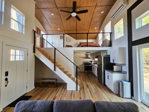 Cozy modern interior of a two-story home with wooden accents, a staircase, kitchen, and living area.