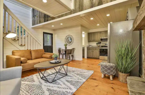 Cozy living area with a sofa, coffee table, and dining space, featuring wooden accents and a modern kitchen.