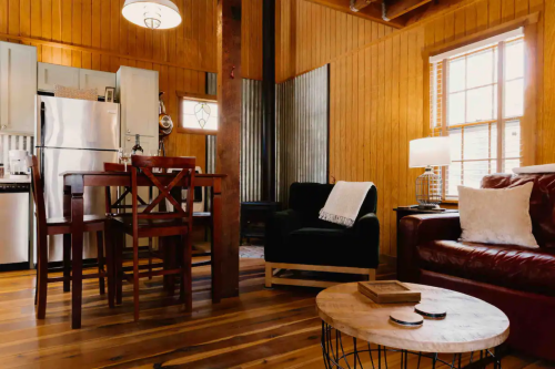 Cozy interior of a wooden cabin featuring a dining area, living space, and rustic decor.