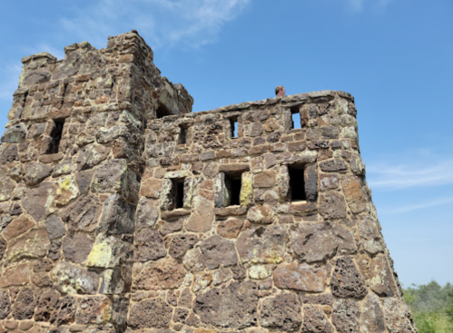 Ruins of a stone structure with multiple windows against a clear blue sky.