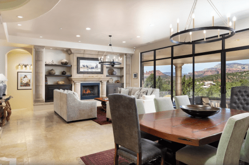 Modern living room with a fireplace, dining area, and large windows showcasing a scenic outdoor view.
