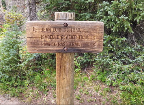 Wooden trail sign with arrows pointing to Jean Lunning Trail, Isabelle Glacier Trail, and Pawnee Pass Trail.