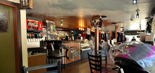 Interior of a casual restaurant with a counter, seating, and decor featuring a mural and beverage dispensers.