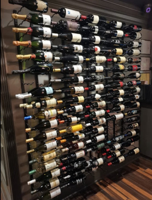 A wall-mounted wine rack displaying a variety of wine bottles in different colors and labels.