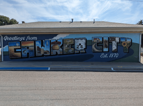 Mural reading "Greetings from Cawker City" with images and the year "Est. 1870" on a building wall.