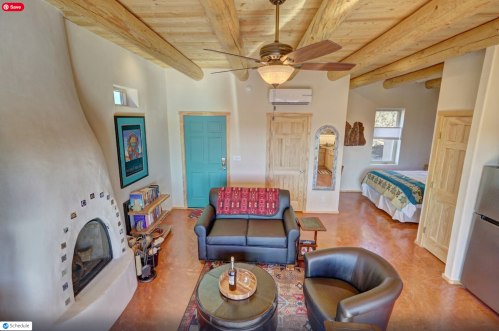 Cozy living area with a sofa, armchair, and rustic decor, featuring a ceiling fan and a small kitchenette.
