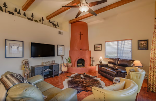 Cozy living room with a fireplace, wooden beams, leather furniture, and decorative accents, including a guitar and artwork.