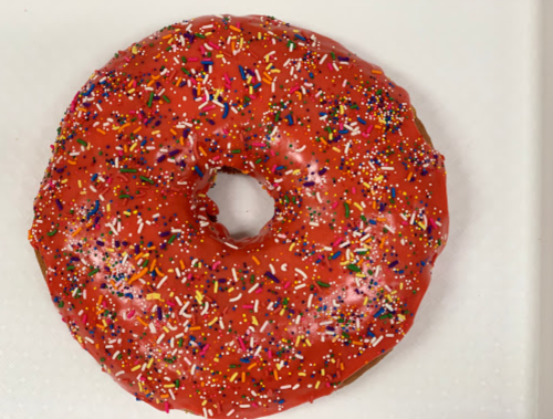 A round donut with bright red icing and colorful sprinkles on top, placed on a white background.