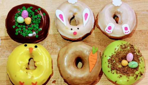 A variety of festive donuts: bunny, chick, and carrot designs with colorful decorations and sprinkles.