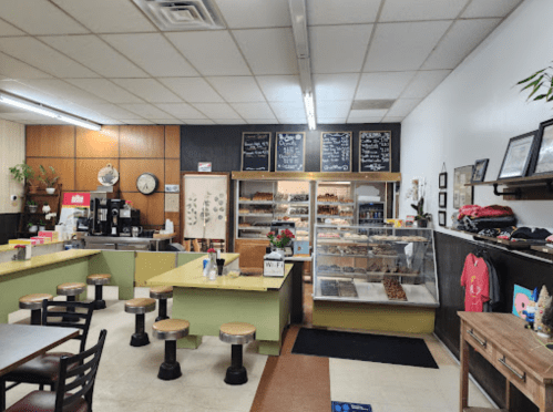 Cozy café interior with a display case of pastries, seating area, and a menu board on the wall.