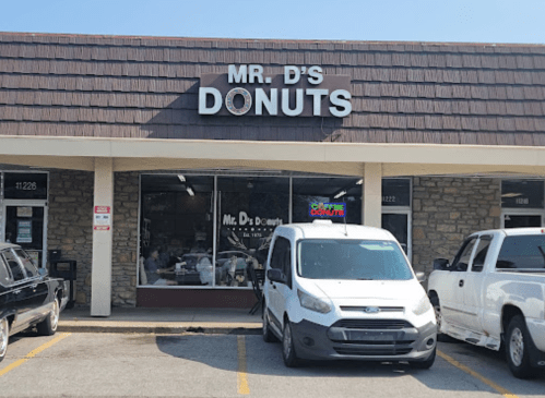 Exterior of Mr. D's Donuts shop with a sign, featuring a white van parked in front.