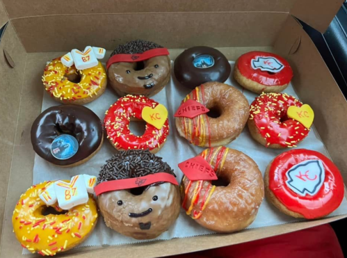 A box of decorated donuts featuring football themes, including team colors and player designs.
