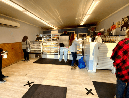 A busy bakery with customers in line, displaying pastries and desserts behind a glass counter.