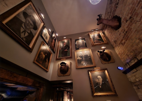 A wall adorned with vintage portraits and mounted animal heads in a rustic setting.
