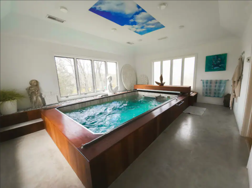 A serene indoor spa with a large pool, wooden accents, and large windows letting in natural light.
