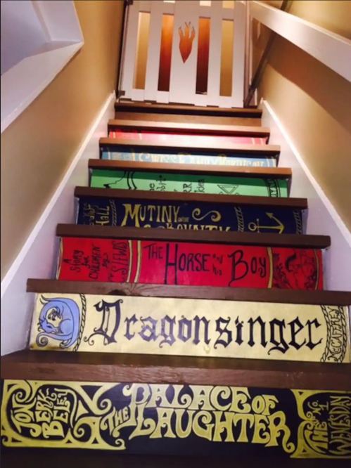 Colorful book-themed stair risers featuring titles like "Dragonsinger" and "The Palace of Laughter."