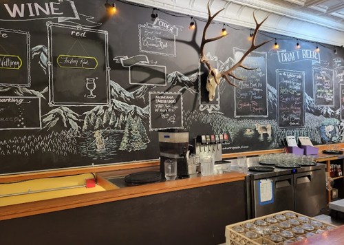 Chalkboard menu with wine, cider, and draft beer options, featuring mountain scenery and decorative antlers.