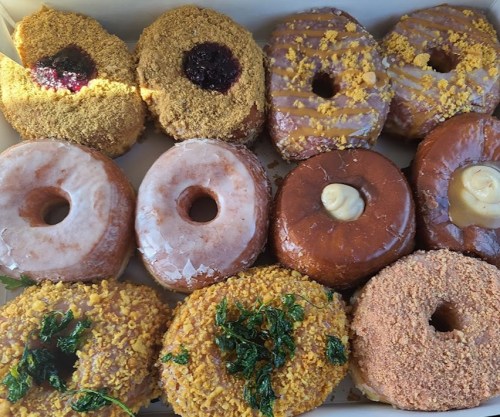 A box of assorted donuts, featuring various toppings like glaze, crumbs, and fillings, arranged in two rows.