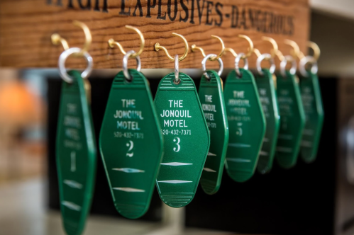 A row of green motel key tags hanging on a wooden board, labeled with "The Jonquil Motel" and numbers.